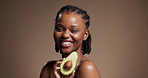 Skincare, face and happy woman with avocado in studio for vitamin c, health and omega 3 oil. Natural beauty, fruit and African model with organic cosmetics, anti aging and brown background space