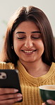 Coffee, phone and smile with woman on sofa in living room of home for break or social media. App, cup and relax with happy Indian person reading mobile text message in apartment for morning me time
