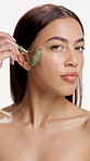 Face, woman or skincare in studio with jade roller for lymphatic drainage, beauty or dermatology. Confident, person or facial tool for blood circulation, healthy skin or wellness on white background.