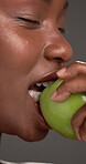 Dental, closeup or black woman in studio with 
apple, mouth or tooth wellness in orthodontics. Face,  eating and female person on gray background with fruit, whitening or dentistry in oral health.