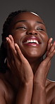 Face, skincare and excited black woman with beauty, self care and wellness in studio. Smile, dermatology and model with makeup cosmetics, touch skin and collagen treatment results on gray background