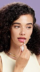 Makeup, lip gloss and woman in studio with cosmetics for hydration, skincare and beauty products. Aesthetic, salon and person with balm for shine, glow and apply moisturizer on purple background