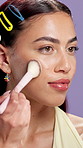 Beauty, makeup brush and smile with face of woman in studio for shine, foundation application or self care. Blush powder, aesthetic and highlighter glow with person on purple background for cosmetics