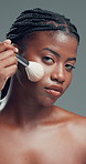 Face, black woman and brush for makeup in studio with beauty, foundation and aesthetic. Portrait, female person and cosmetic tools for makeover, facial powder and natural shine on gray background