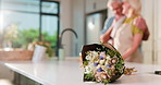 Flowers, home and old couple in kitchen, love and bonding together with present, care and trust. Apartment, man and woman with gift, retirement and bouquet with anniversary, romance and relationship