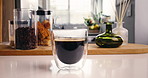 Coffee, glass and liquid in home kitchen for strong caffeine, latte or cappuccino for roast. Organic brew, drink and beans or brown froth for mocha, espresso or breakfast beverage in house for aroma