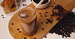 Above, beans and iced coffee on table in kitchen for morning beverage, brewing and cappuccino liquid. Espresso shot, drink and latte cup on board, aesthetic presentation and setup for strong caffeine