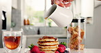 Maple syrup, tea and pancakes with hand in kitchen for strawberry, nutrition and health. Fruit, food and dessert or brunch with person and honey on hotcakes in home for snack, breakfast and drink