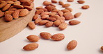 Nutrition, almonds and fall on table for health, food or natural diet for wellness. Wooden counter, nuts and organic snacks for vegan, vegetarian protein and vitamins with minerals for benefits