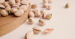 Healthy, pistachio and nuts on board in studio with natural textures, organic food and grain production. Seeds, products and roasted for harvest season, quality control and vegan snack with nutrition