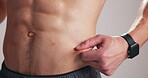 Man, body and pinch on abdomen for stomach, progress or diet on studio background. Health, fitness and male model with abs to track exercise, training results and muscle goals or weight loss target
