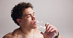 Tired, man and drinking water for fitness in studio for hydration, refreshing and exercise break. Athlete, person and bottle with liquid for training recovery, mineral beverage and white background