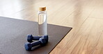 Yoga, equipment and dumbbells with water on mat for fitness, workout and health routine. Empty room, beverage and floor with weights for exercise, physical activity and practice in wellness center