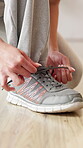 Fitness, hands and woman tie sneakers at health club to start workout, exercise preparation or routine. Floor, person and shoelace in studio for training comfort, physical activity and getting ready