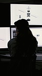 Back, computer screen and satellite development with woman in dark office for surveillance equipment. Display, monitor and space technology with engineer in workplace for infrastructure maintenance