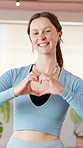 Heart, shape and face of woman for fitness, exercise and training in health club. Gym studio, portrait and female person with love, emoji and hand gesture for wellness, workout or cardio support
