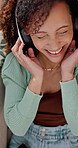 Dancing, phone and happy woman with headphones on couch, streaming music and unwind on weekend. Chilling, mobile and person listening with audio tech in home, hip hop track and moving to rhythm.