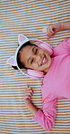 Face, headphones and top view of child in bed at home for streaming service, sound and radio. Above, happy girl and kid listening to audio, song and dance to music playlist in bedroom to relax