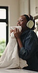 Smell, home and black woman with smile, laundry and cleaning with headphones, chores and linen. Housekeeping, happy and African person in lounge, soft fabric and domestic worker with fresh scent