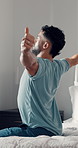 Man, morning and awake with stretching on bed for flexibility, daily routine or fresh start in home. Male person, relax and sunlight in bedroom with warm up for new day, beginning or break in house