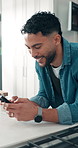Happy, home and man with smartphone, typing and social media with communication. Apartment, mobile user and person in kitchen, smile and cellphone with connection, texting and message to contact