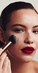 Beauty, blush and face with woman in studio for cosmetics, facial or makeover routine. Apply, freckles and makeup brush with model on white background for aesthetic, change or transformation