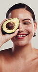 Face, woman and avocado with beauty in studio of skincare, hydration and facial healing. Portrait, person and tropical fruit with natural glow, healthy skin and collagen treatment on white background