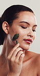 Woman, relax or skincare in studio with jade roller for blood circulation, puffiness or dermatology. Smile, person or facial tool for lymphatic drainage, healthy skin or wellness on white background.