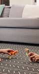 Children, hands and playing with dinosaur toys for playful childhood, imagination or bonding. Closeup, kids or siblings with animal raptors for fossil game, attack or cognitive skill on floor in home