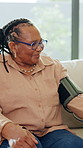 Blood pressure, healthcare and senior black woman on sofa in living room of home for appointment. Checkup, medical and sphygmomanometer with old African person in apartment for advice or consulting