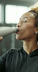 Woman, fitness and drinking with bottle in gym for water, hydration or recovery in health club. Active, female person or thirst with mineral liquid, rest or break for workout, exercise or training
