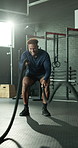 Man, fitness and battle rope with arm exercise for muscle training or endurance in gym. Active, male person or stamina with strong cable swing for strength workout, balance or grip in health club