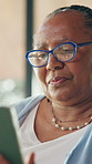 Tablet, glasses and senior black woman in home reading online news bulletin on weekend morning. Digital technology, relax and African elderly female person with blog post on app for entertainment.