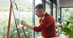 Man, artist and painting on easel at house for drawing, watercolor and nature sketch for artwork. Mature person, window and outdoor inspiration for picture, art creation and self expression of hobby