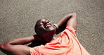Rest, exercise and tired black man on road for recovery after workout, running and training outdoor. Happy, sports and person relax, breathe and laying on street for wellness, health or fitness break