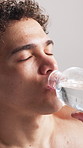 Fitness, tired and man drink water in studio for wellness, workout recovery and health. Bottle, thirsty athlete and hydration for exercise break, breathing or refreshing liquid on white background