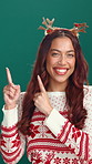 Christmas, promotion and pointing with face of woman in studio for deal, announcement or sale. Giveaway, space and celebration with happy person on green background for festive season or marketing