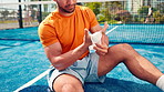 Bandage, hand pain and man on padel court with injury, medical crisis and accident outdoors. Fitness, health and person with ache, strain and hurt from training, workout and exercise for tennis game