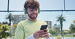 Fitness, man outdoor and headphones with phone for music, padel match preparation and text message. Happy, person and athlete on tennis court with tech for audio, online chat and social media post.