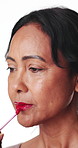 Woman, apply red lipstick and makeup in studio with smile, beauty aesthetic and glowing skin. Happy, mature person and bold lip gloss for shine, confidence and vibrant cosmetic on white background.