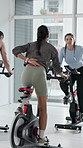 Spin class, cardio and women on bike, fitness and training routine for physical activity and health. Gym, personal trainer and people on machine for body strength, mobility and cycle for wellness