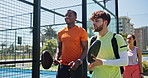 Men, friends and talk at tennis court, laugh and excited for game with padel at fitness club. People, happy and athlete with team, partnership or conversation with equipment for contest at park