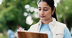 Outdoor, volunteer or woman with clipboard, charity event or community service with schedule. NGO project, documents or person with planning, nonprofit sign up ir inventory for donations or checklist