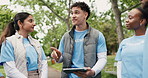 Volunteer, outdoor and man with tablet, planning or discussion with social responsibility. Group, men or women in park, feedback or app with charity event, community service or NGO project with unity