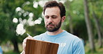 Clipboard, man and volunteer outdoor with planning for social responsibility, ngo or charity event. Writing notes, nature and male person with checklist or schedule for community outreach in park.