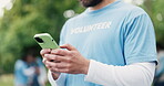 Hands, phone and volunteer man in park for charity, community outreach or donation update. App, search and typing with activist person outdoor for social media post of ngo or non profit mission