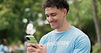 Funny, phone and volunteer man outdoor for charity, community outreach or donation update. App, laughing and typing with happy activist in park for social media post of ngo or non profit mission