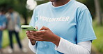 Hands, phone and volunteer woman in park for charity, community outreach or donation update. App, contact and typing with activist person outdoor for social media post of ngo or non profit mission