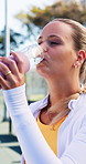 Tennis player, woman or drinking water with bottle for sports hydration, match or competition break. Active, person and athlete on court with beverage for electrolytes, tournament rest and recovery.