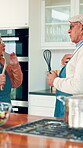 Cooking, singing and love with old couple in kitchen for bonding, support and connection. Karaoke, meal prep and music with senior man and woman in home for romance, entertainment and relationship